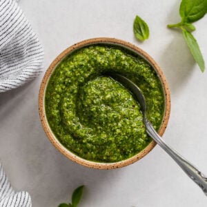 Basil pesto in pottery bowl with spoon.