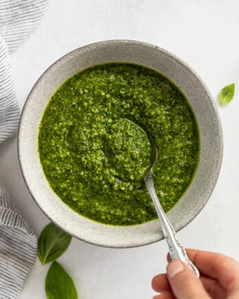 Bowl of pesto with hand taking a spoonful.