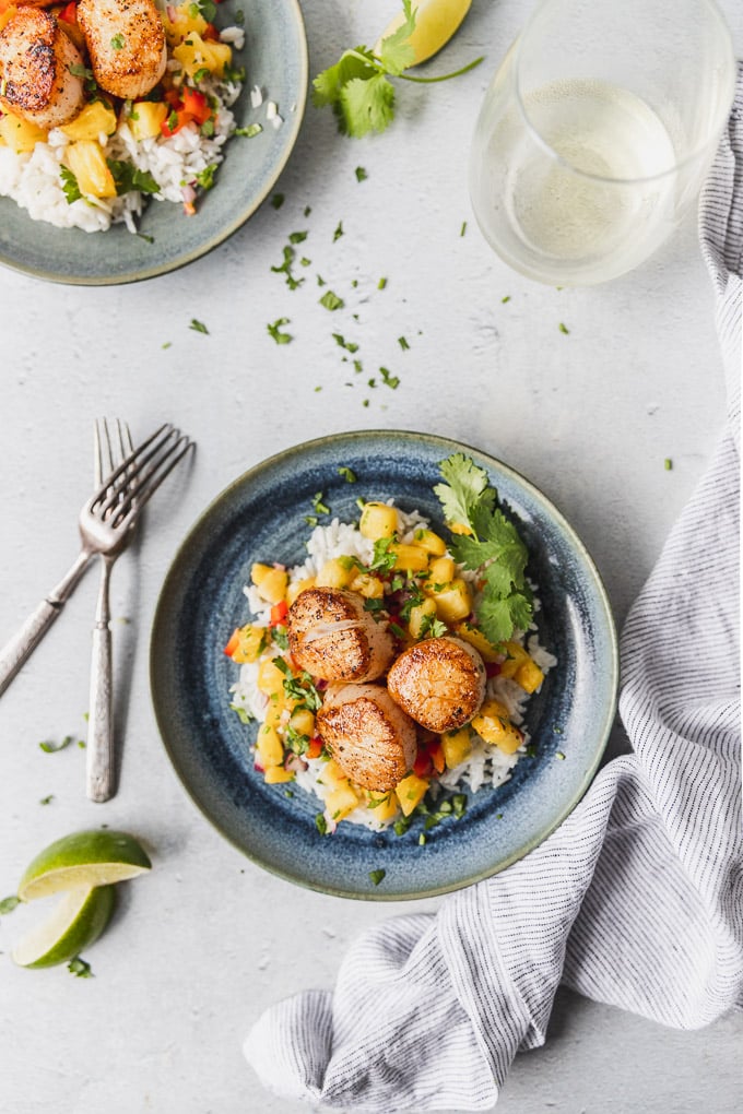 Overhead look at seared scallops on blue plate with pineapple salsa and coconut rice.
