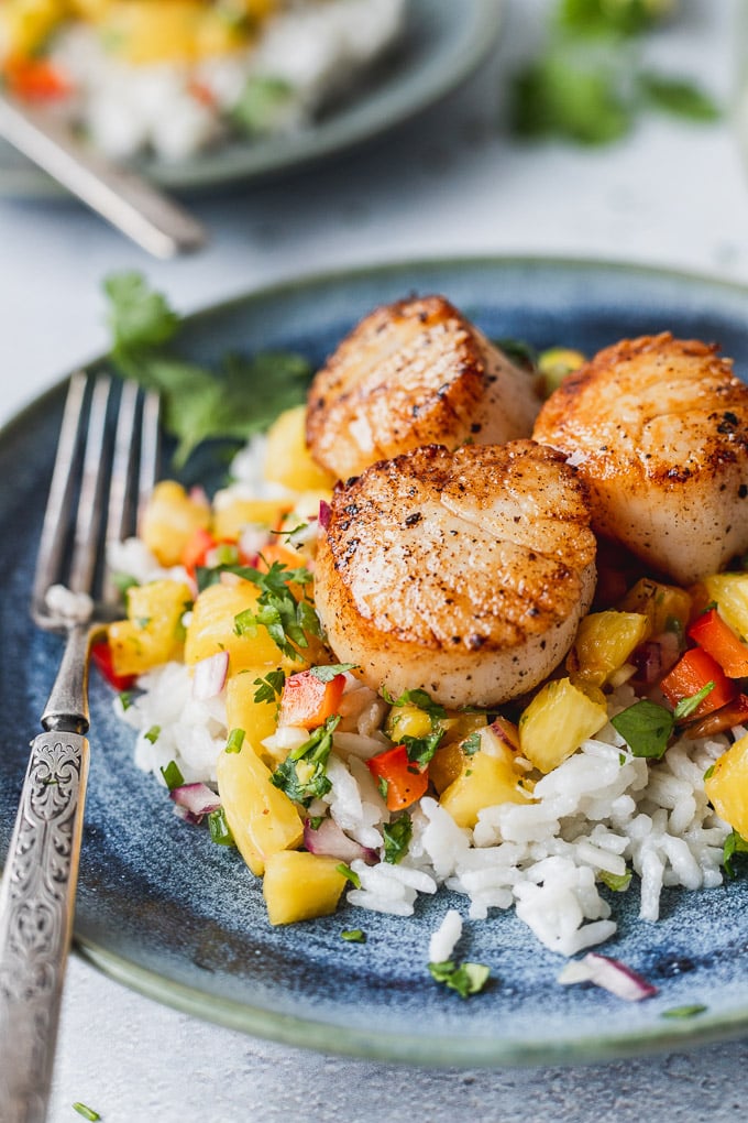 Seared scallops on rice with fork.