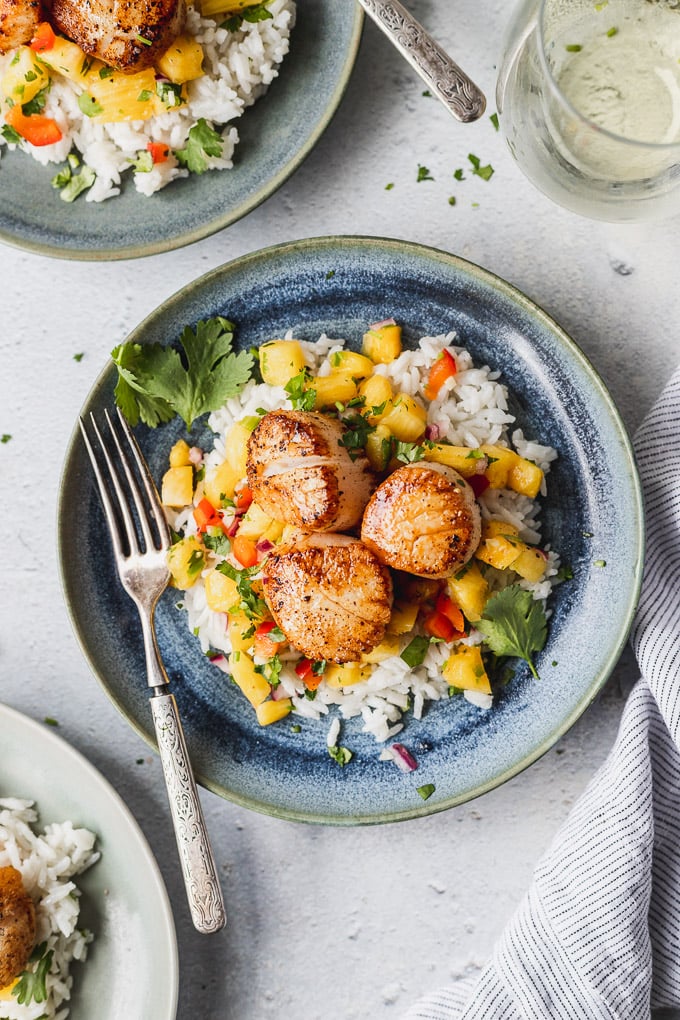 Seared scallops on blue plate with pineapple salsa and coconut rice.