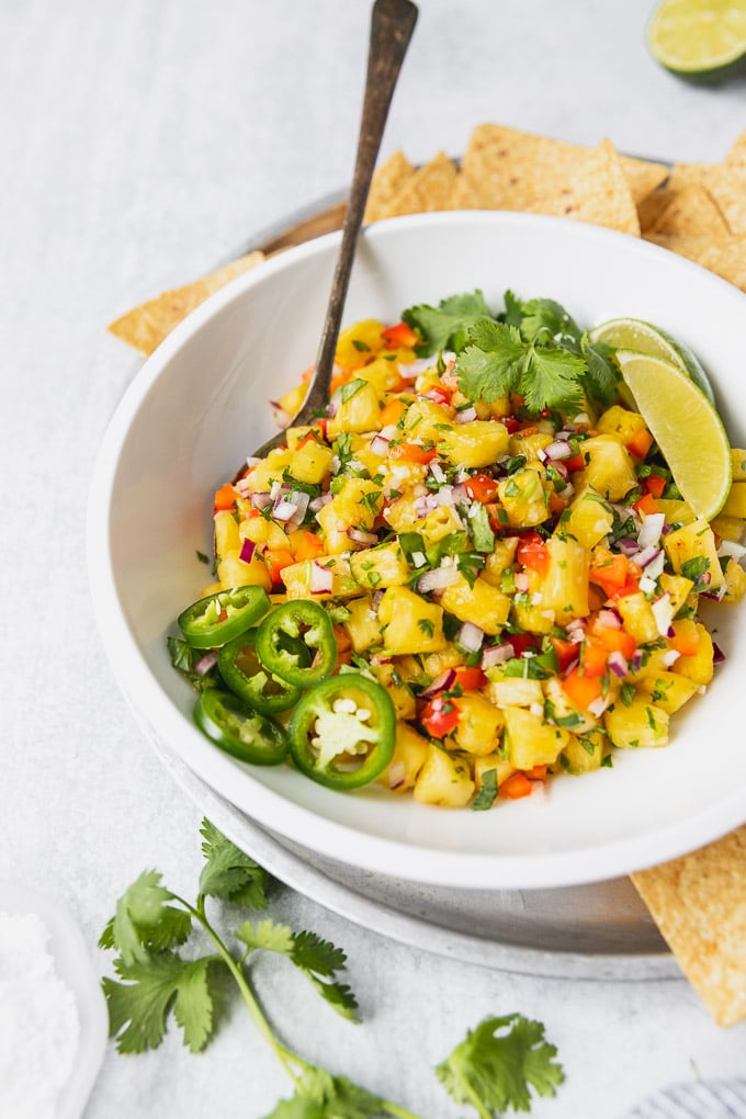 bowl of pineapple salsa with jalapenos and cilantro with spoon and chips