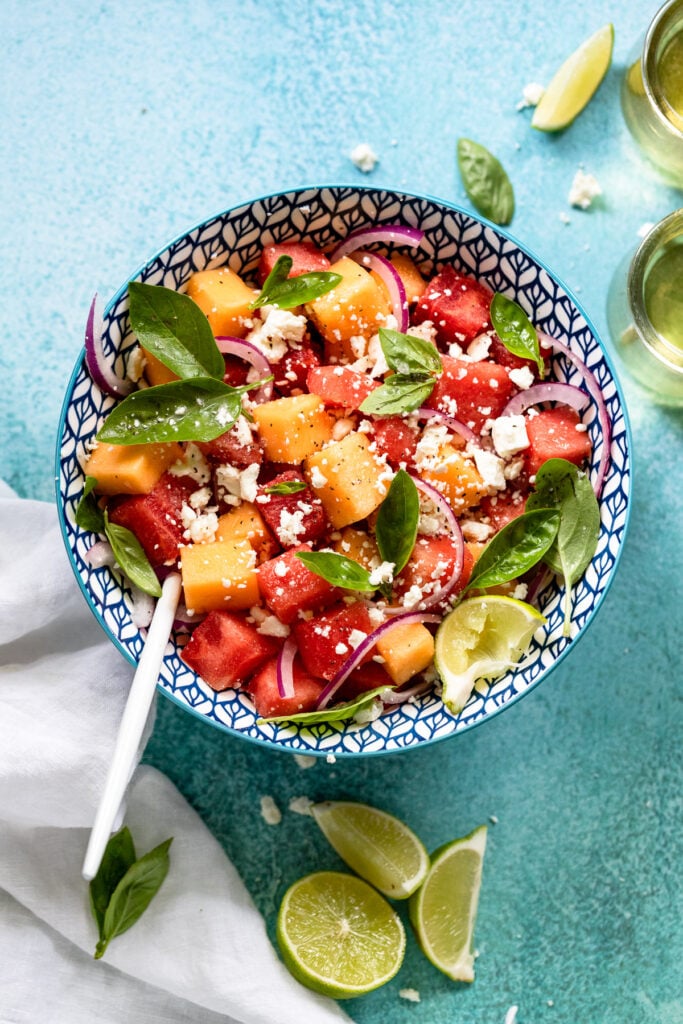 Bowl of melon salad with fresh basil leaves.