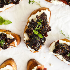 Fig and goat cheese crostini on parchment paper.