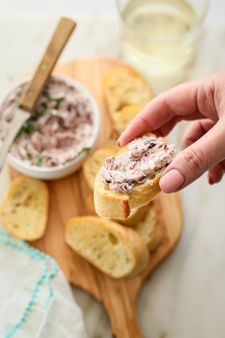 Hand holding crostini with olive butter