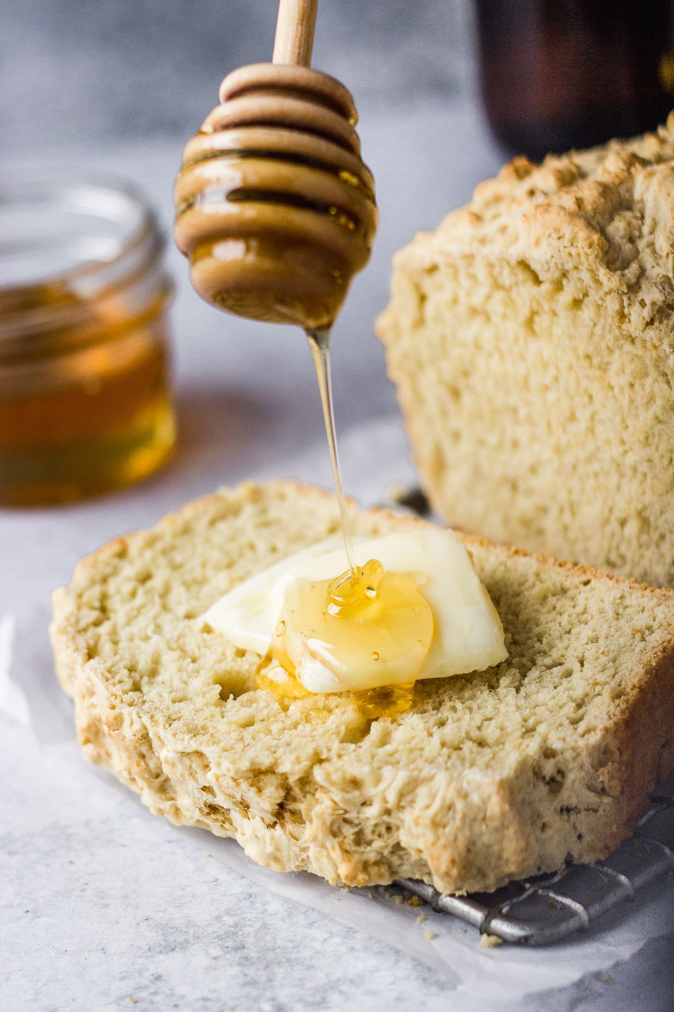beer bread loaf sliced with butter and honey being drizzled on top