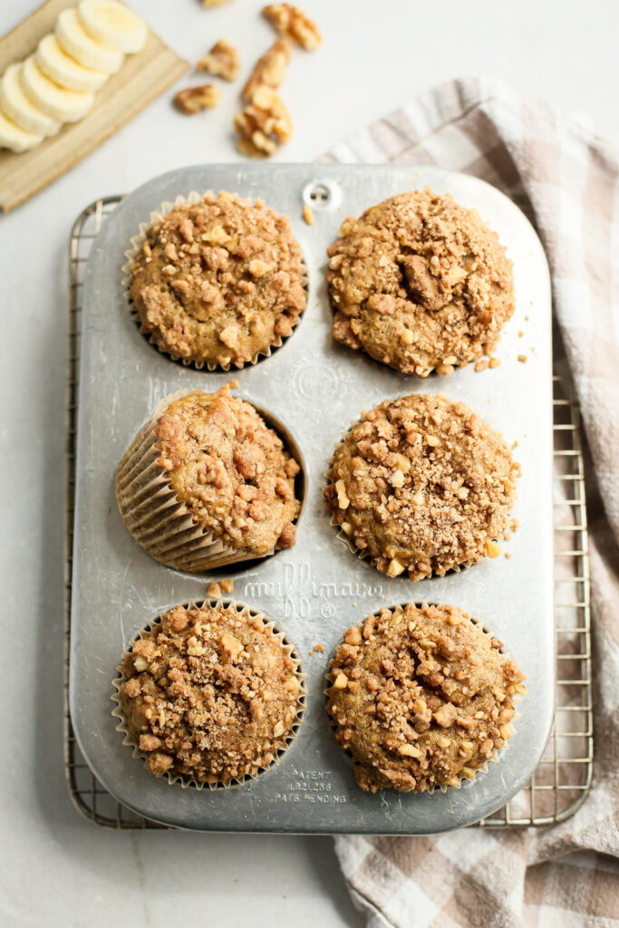 Banana nut muffins with streusel topping in tin after baking.