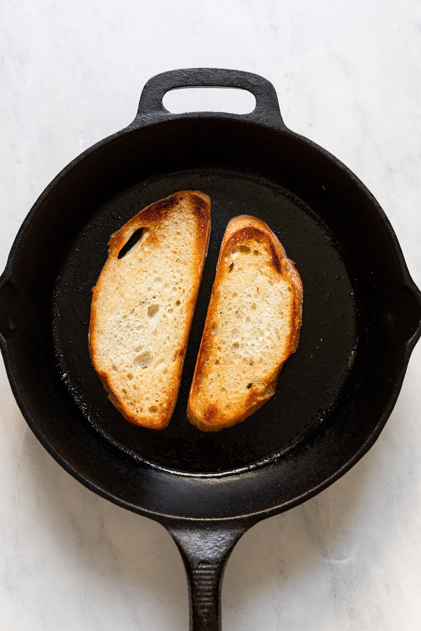 Bread slices in cast iron skillet after toasting.