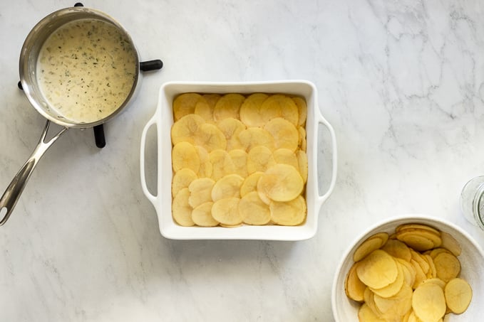 casserole pan with layer of sliced potatoes.