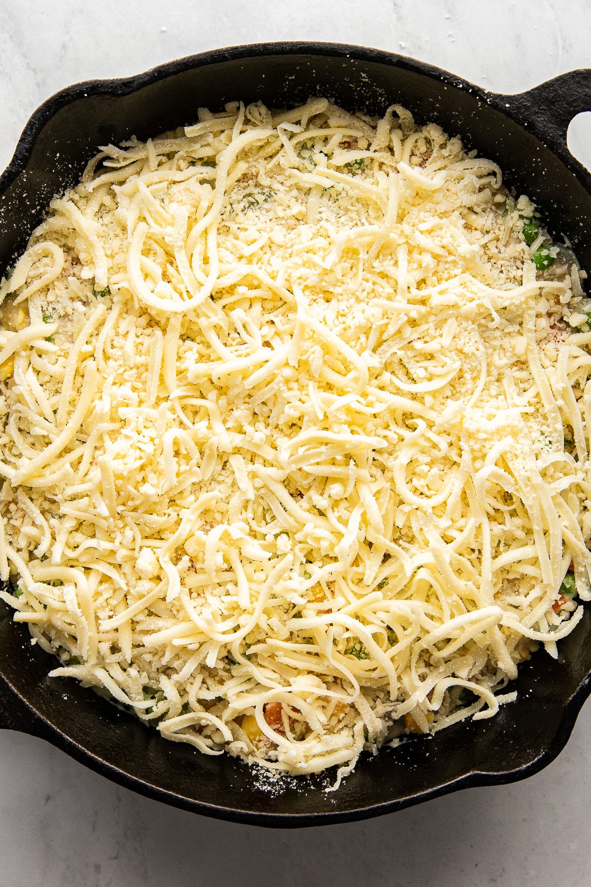 Skillet with shredded cheese on top.