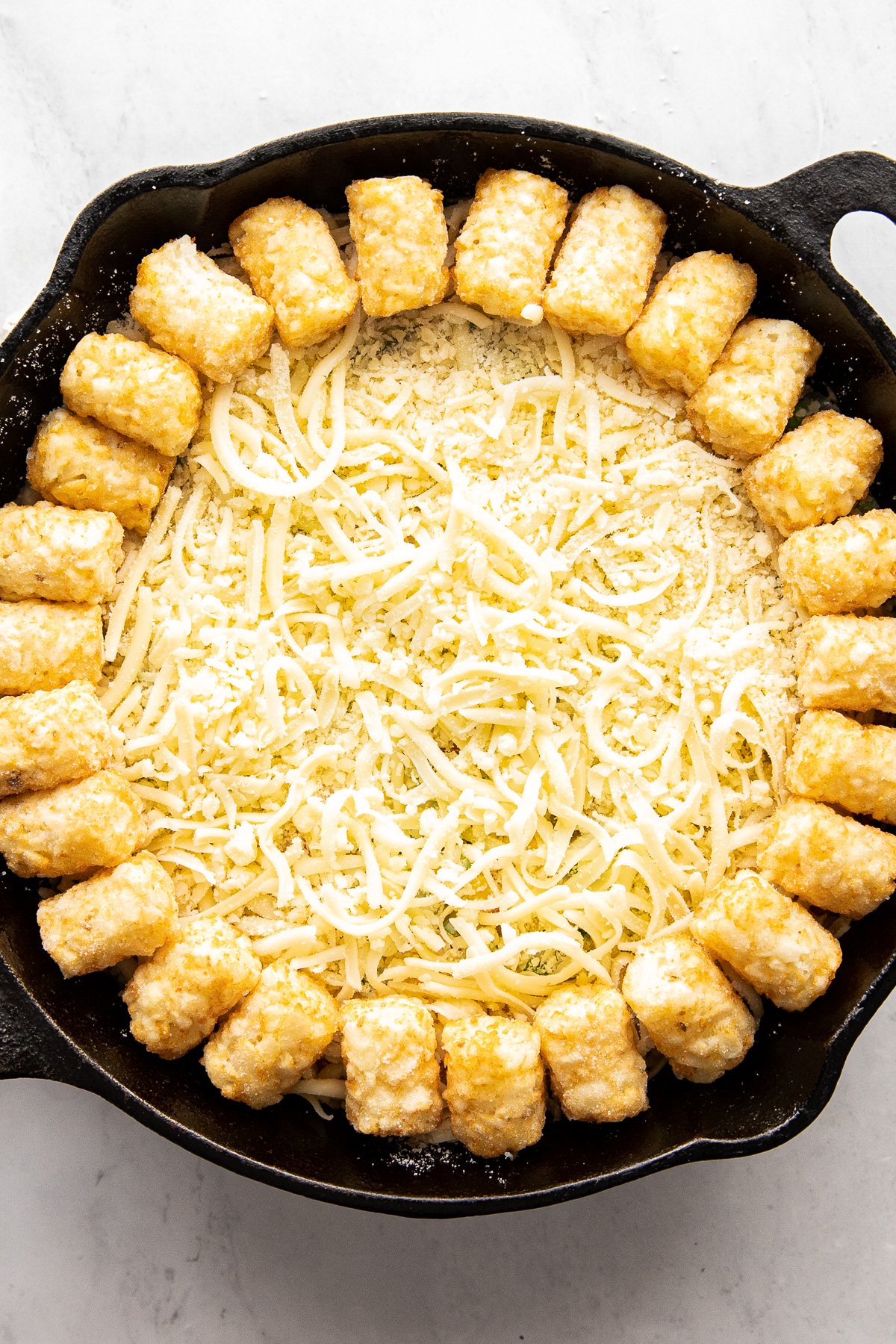 Tater tots in first circle around hotdish in skillet.