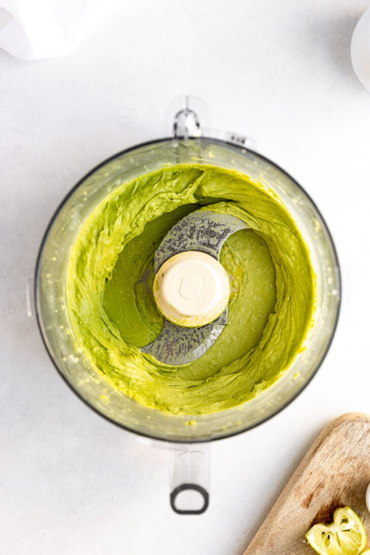Avocado sauce in bowl of food processor after blending.