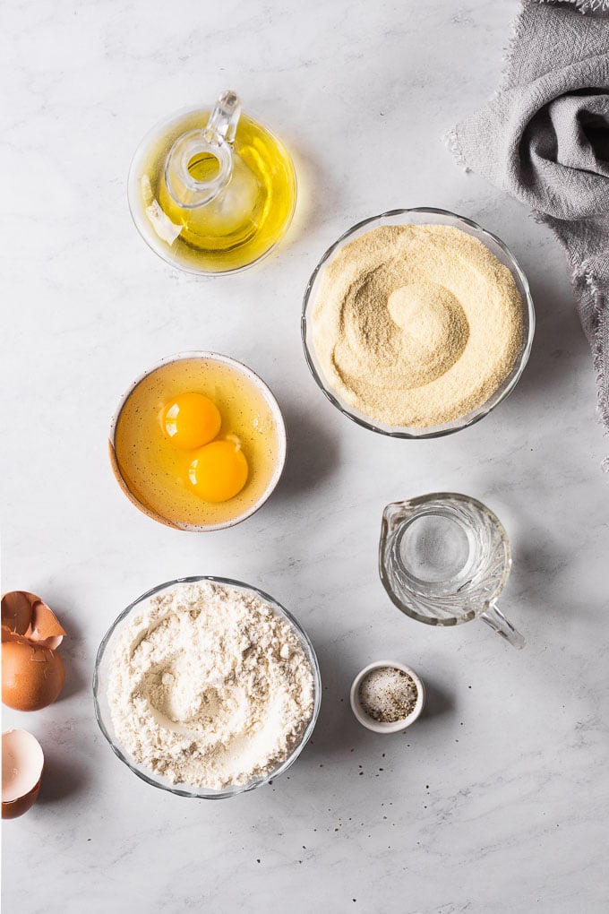 Eggs, all-purpose flour, semolina flour, and olive oil in bowls.