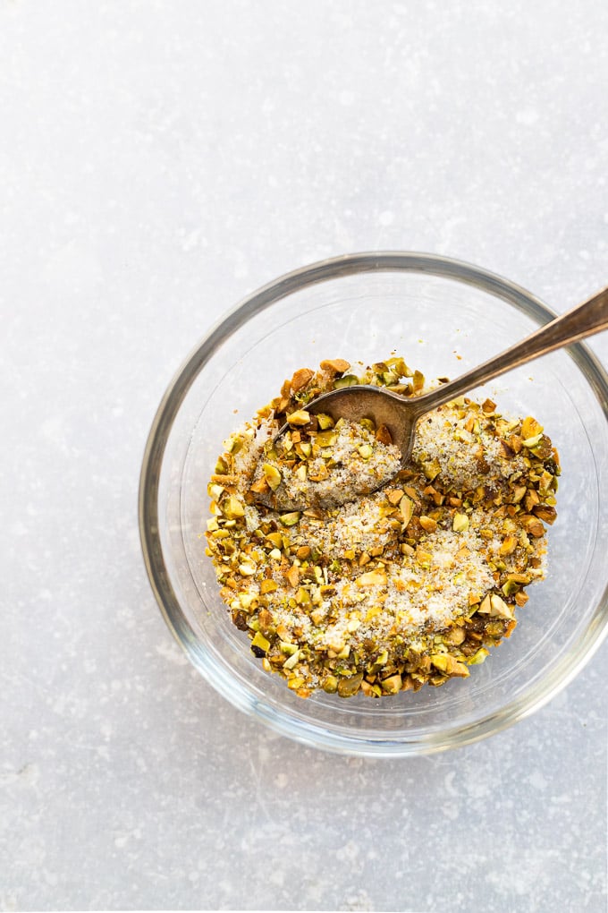 Sugar and pistachio mixture for rolling in a bowl with spoon.