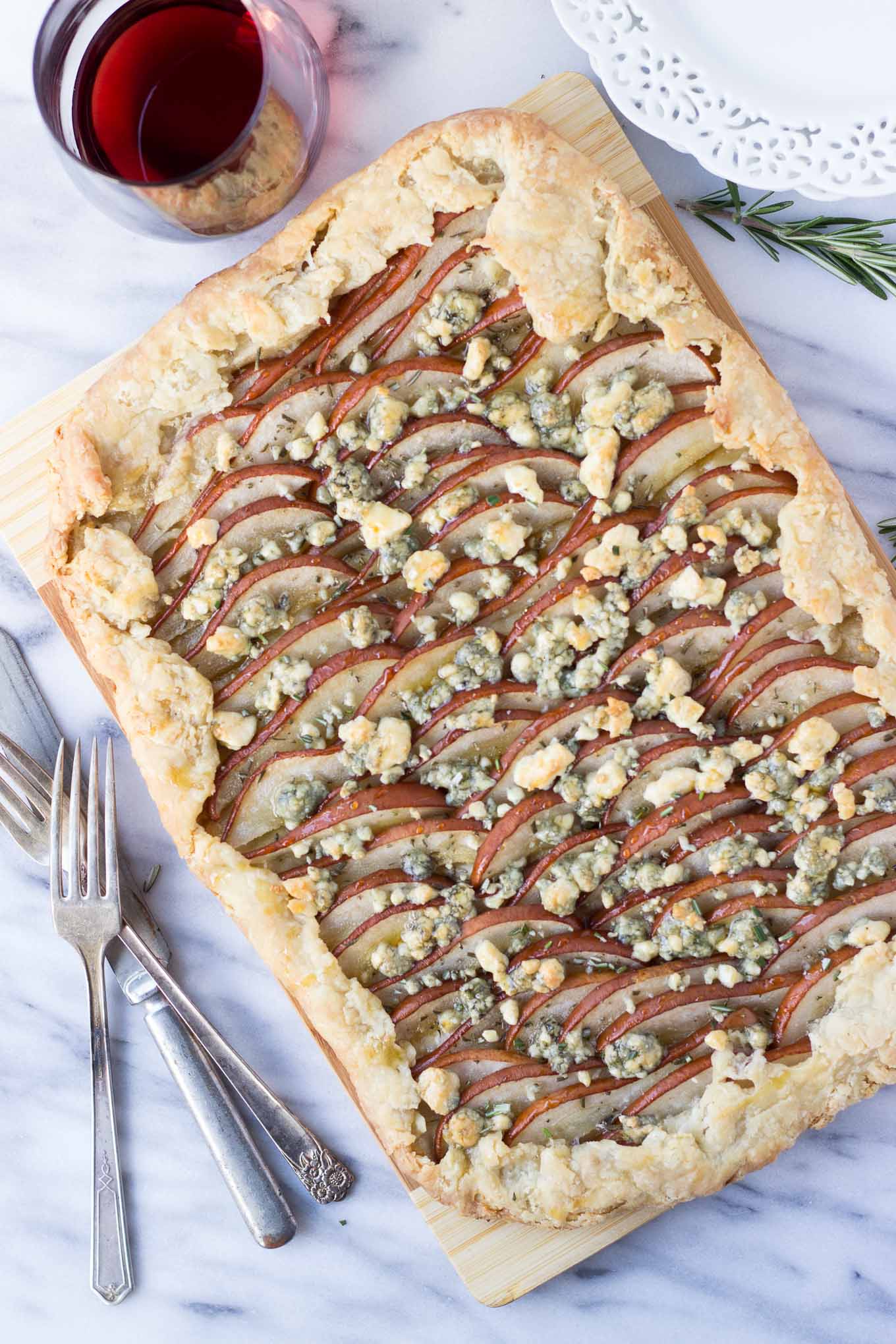 Savory Pear Tart - a flakey crust topped with Bosc pears, rosemary, gorgonzola, and drizzled with honey for the delicate balance of sweet and savory! Excellent for a night-in with wine or as a holiday appetizer.