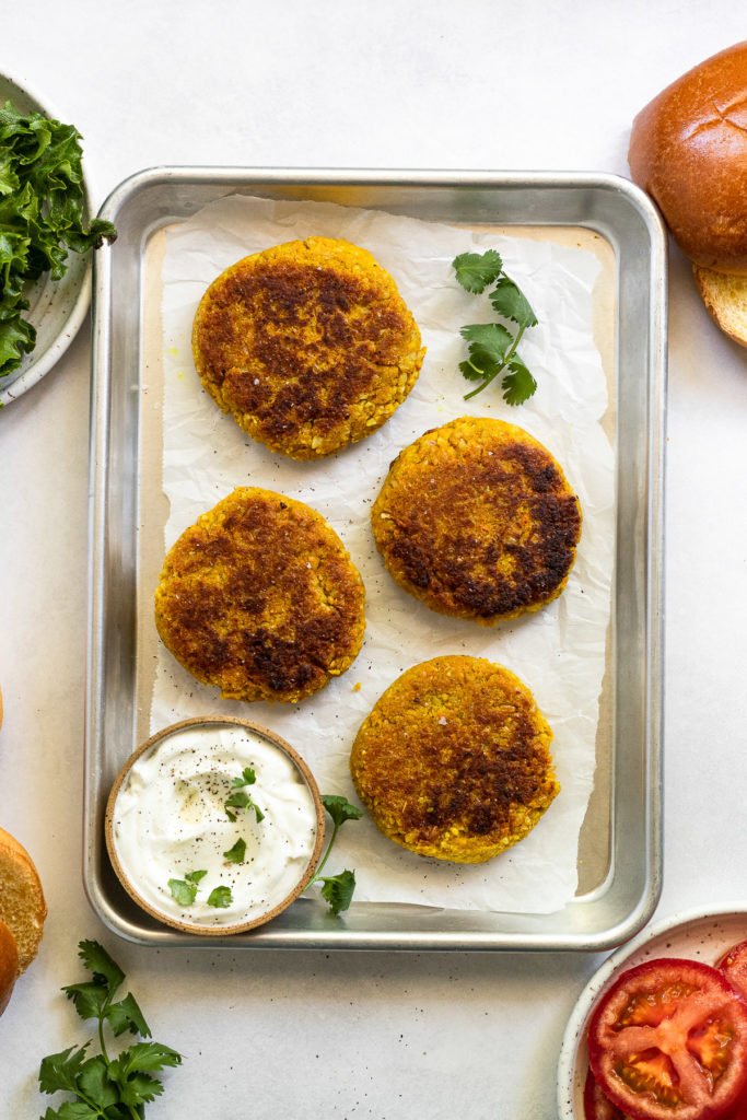 Cooked chickpea burger patties on tray.