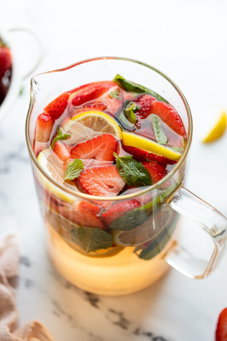 Pitcher of strawberry rose sangria with mint and lemon slices.