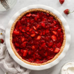 Strawberry pie in pie plate next to linen.