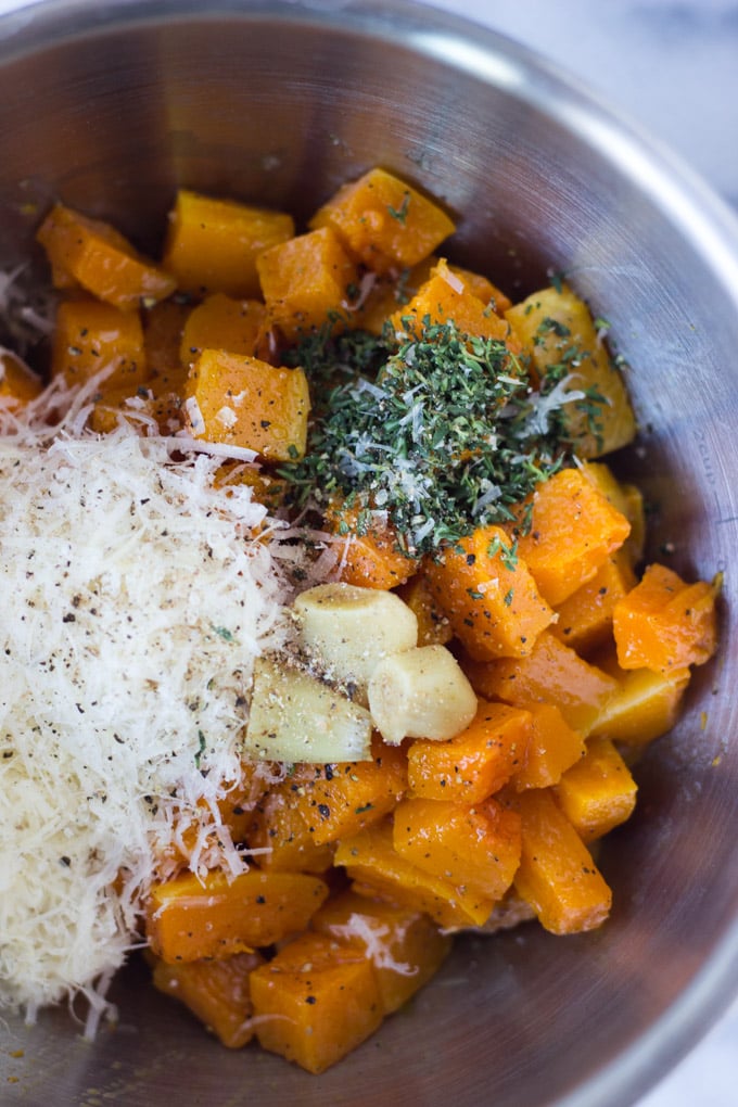 Bowl of roasted butternut squash, thyme, parmesan cheese, and garlic.