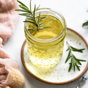Rosemary simple syrup in jar with rosemary sprig.