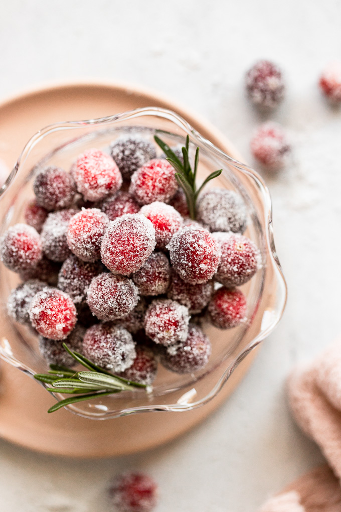 Sugar coated cranberries in bowl on pink plate.