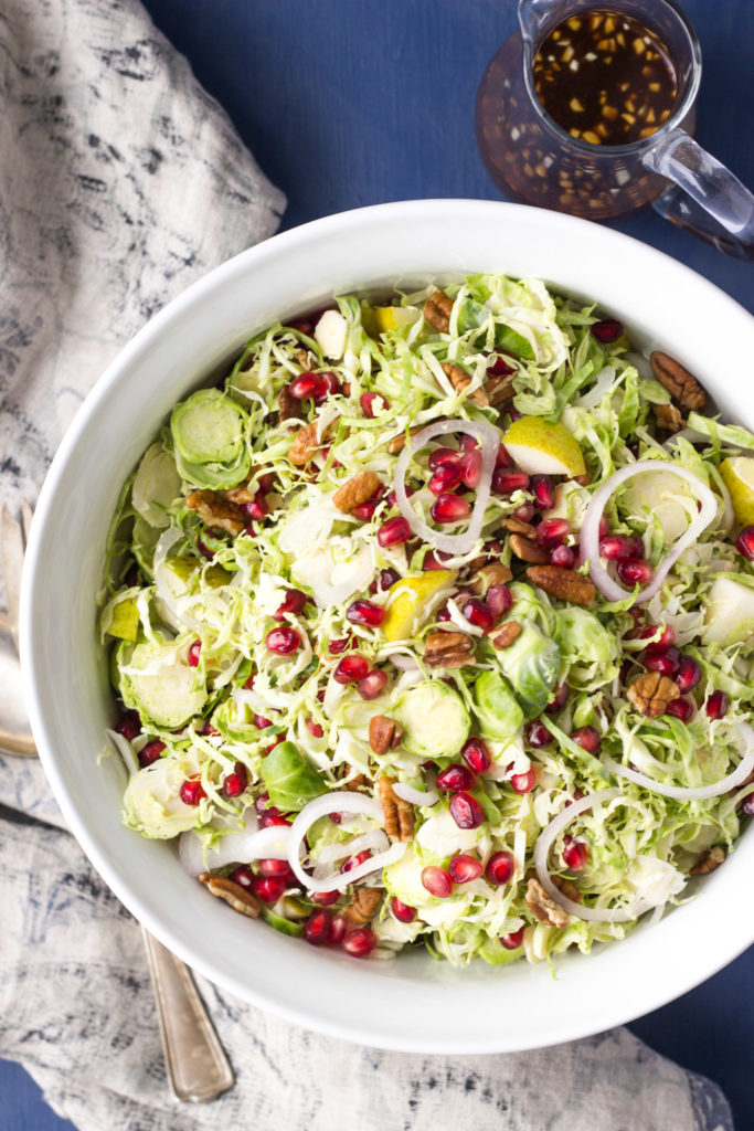 Overhead look into salad bowl with shaved brussel sprouts and pomegranate.