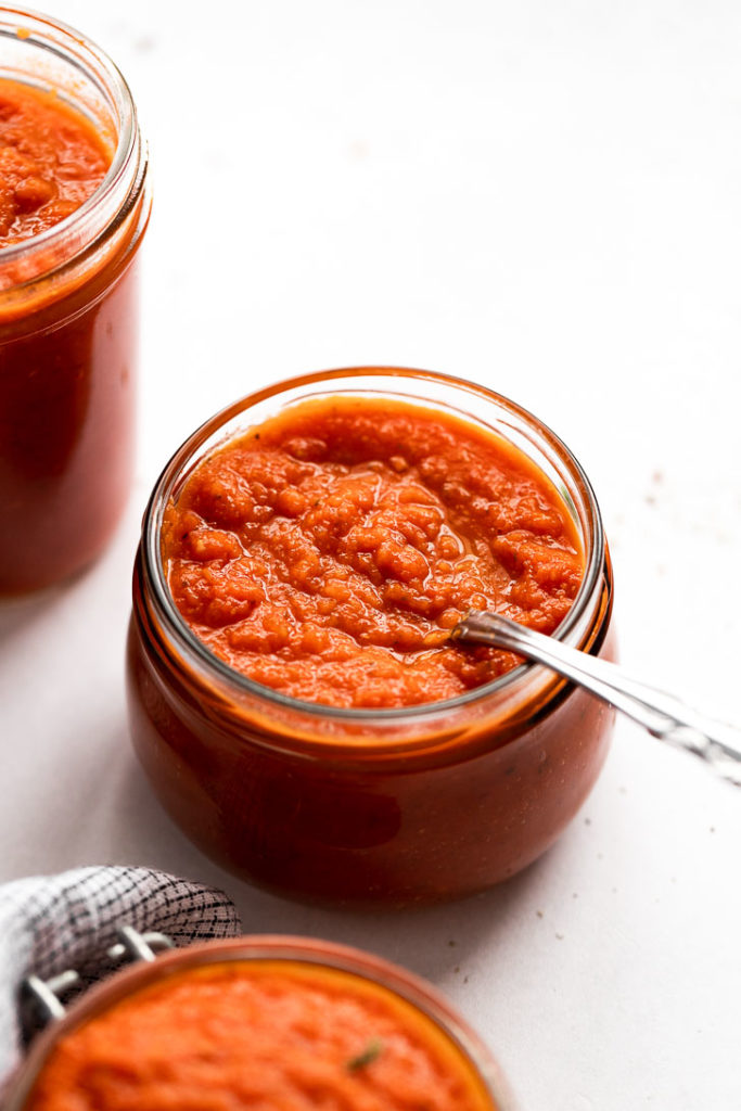 Jar of tomato sauce with spoon.