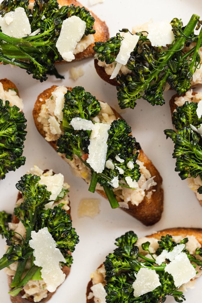 Broccolini and white bean crostini on plate up close.