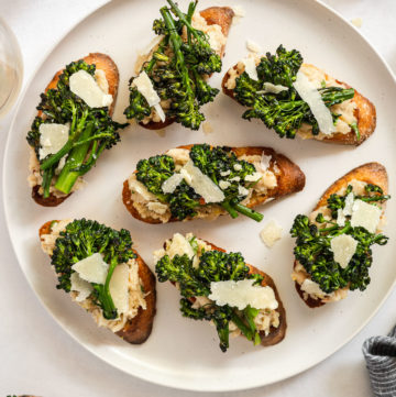 White bean crostini with broccoli on plate.