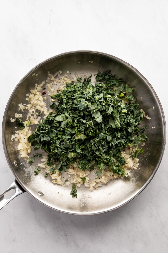 Raw kale added to skillet.