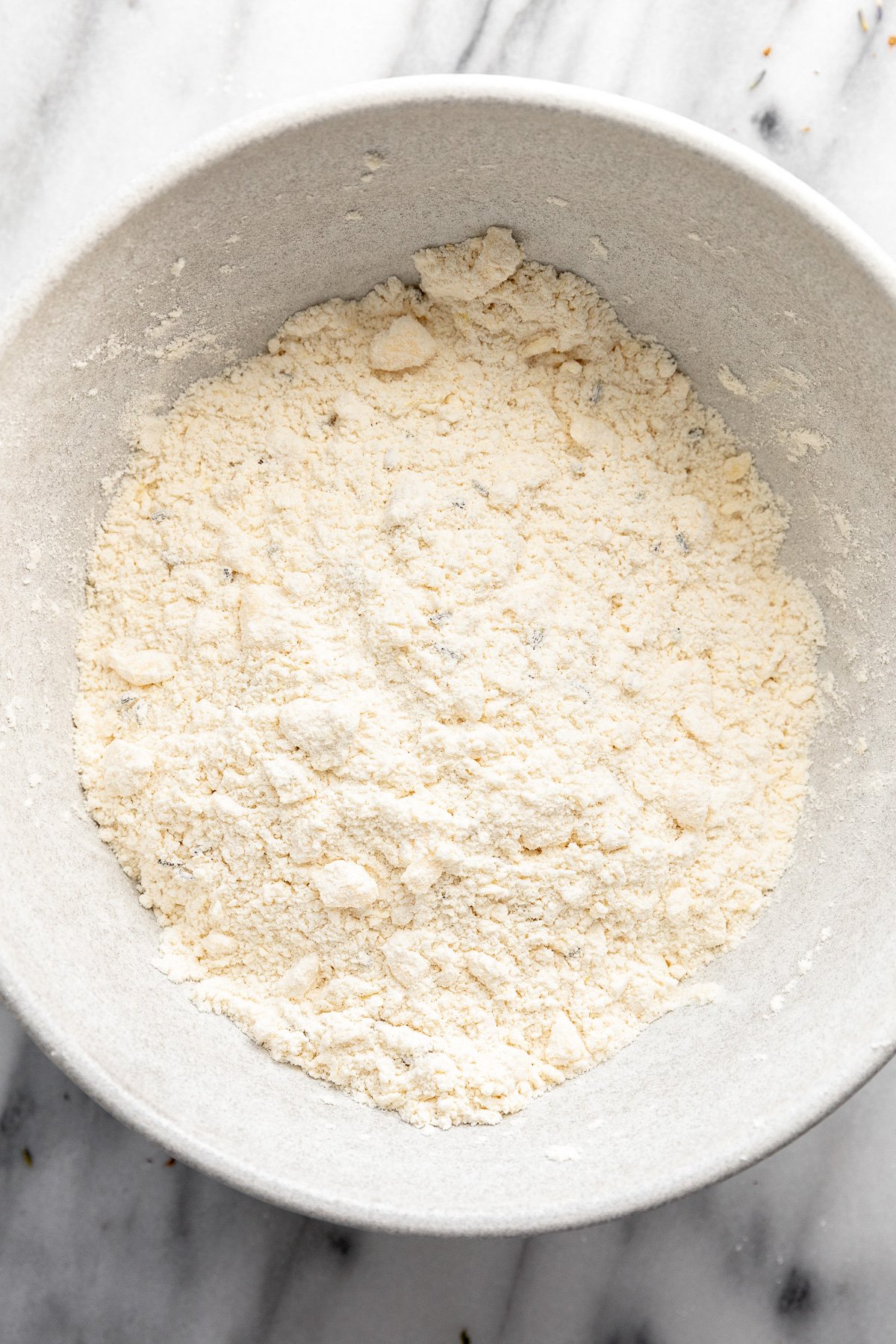 Bowl of flour with bits of butter cut into it.