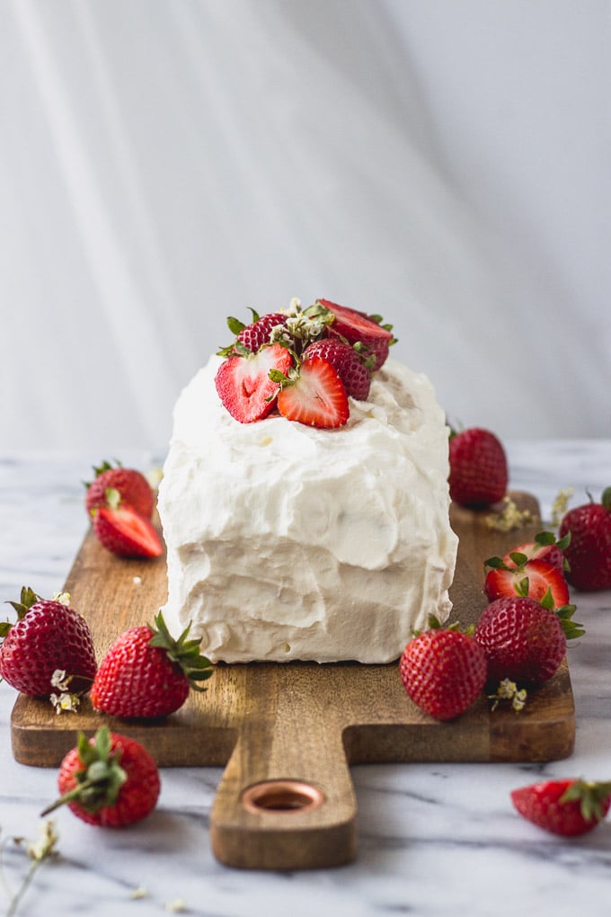 Angel Food Cake with Strawberry Filling frosted on cutting board.