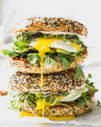 Stack of bagel sandwiches with egg yolk dripping down.