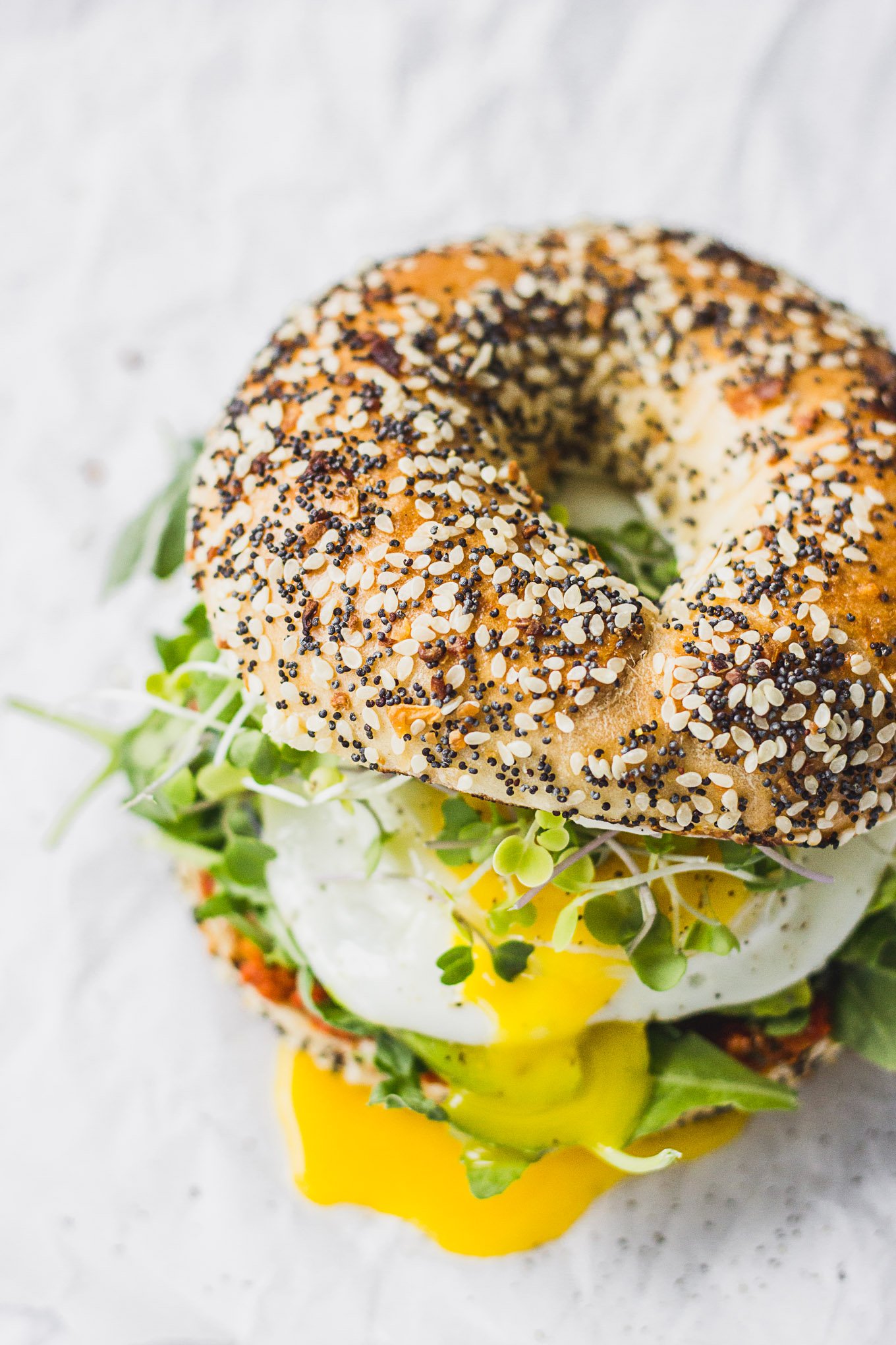 Up close everything bagel with egg yolk seeping out.