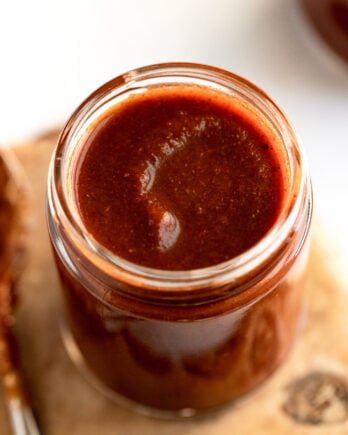 Jar of red enchilada sauce next to spoon.