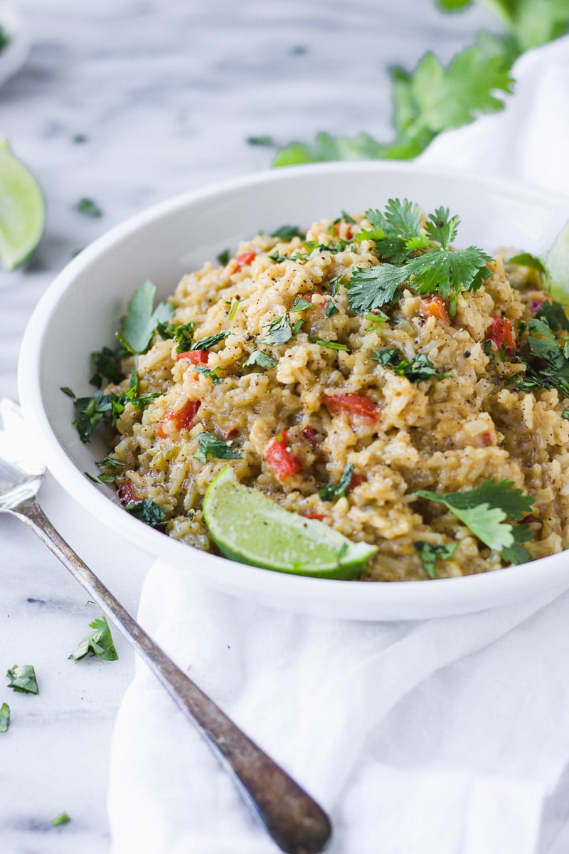 white bowl with cheesy mexican rice, limes, and cilantro