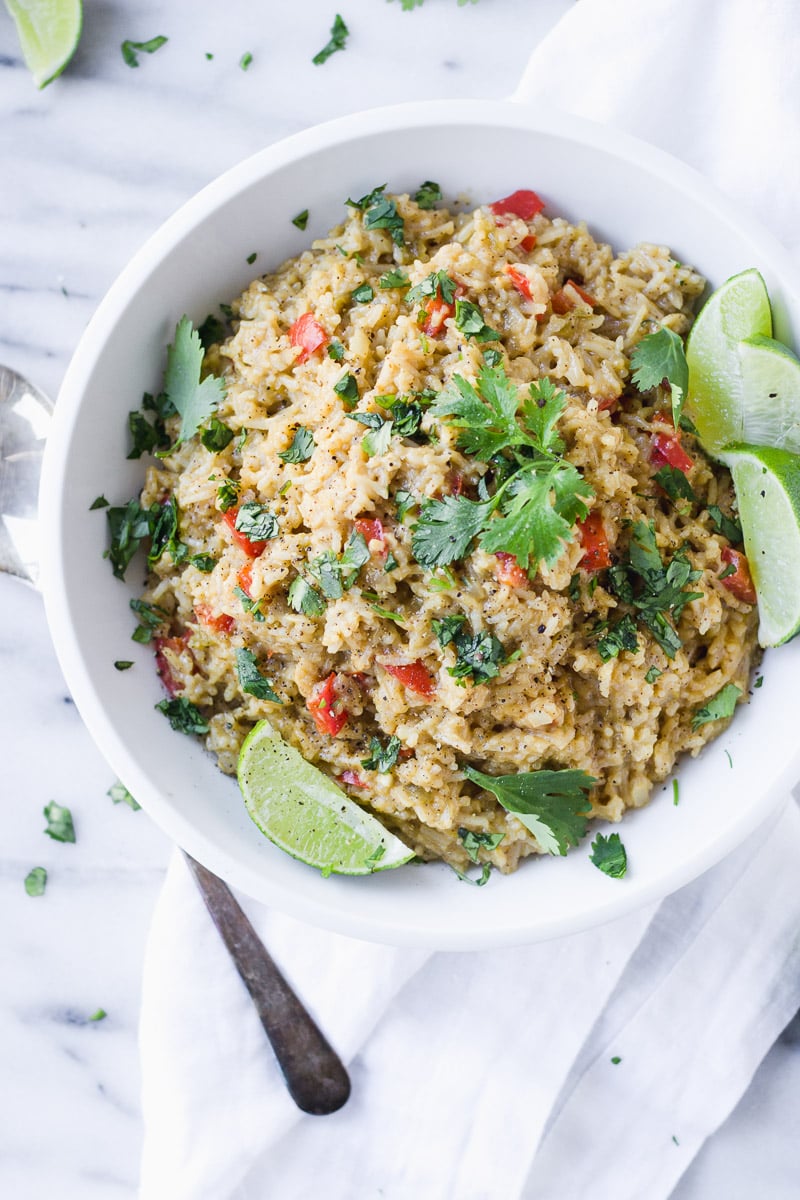 white bowl with cheesy mexican rice, limes, and cilantro