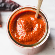 red enchilada sauce in a jar with a spoon