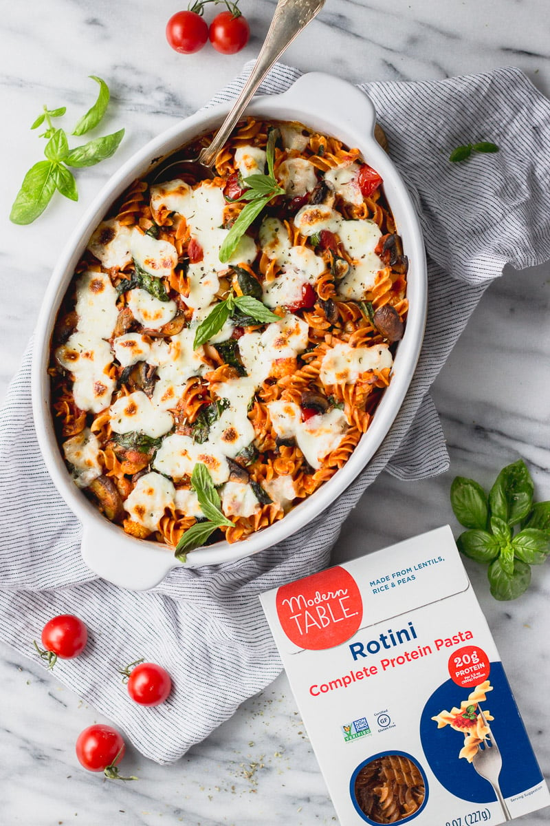 vegetable baked pasta overhead with basil in white casserole dish