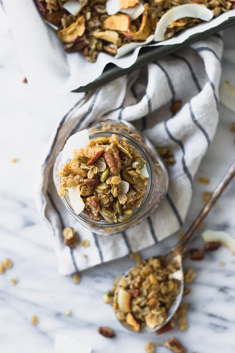 easy autumn spice granola on spoon and in jar by fork in the kitchen