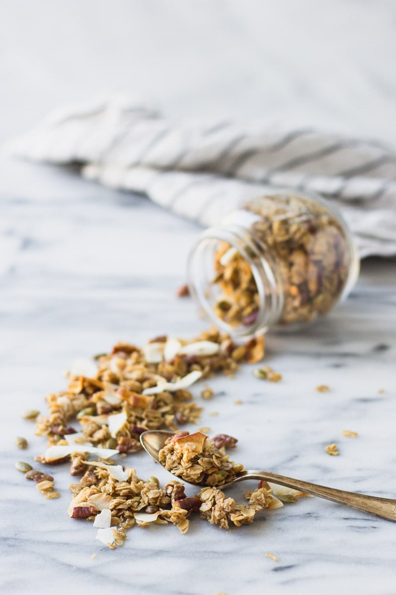easy autumn spice granola pouring out of jar by fork in the kitchen