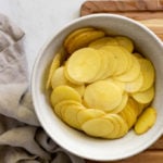 bowl of thinly sliced potatoes.