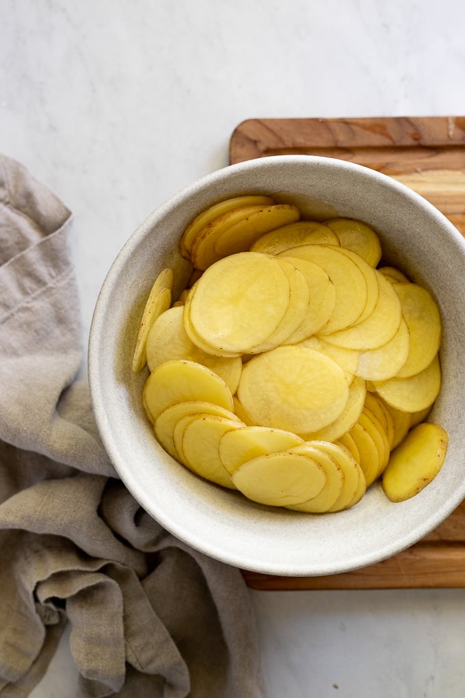 Thinly sliced potatoes in bowl.
