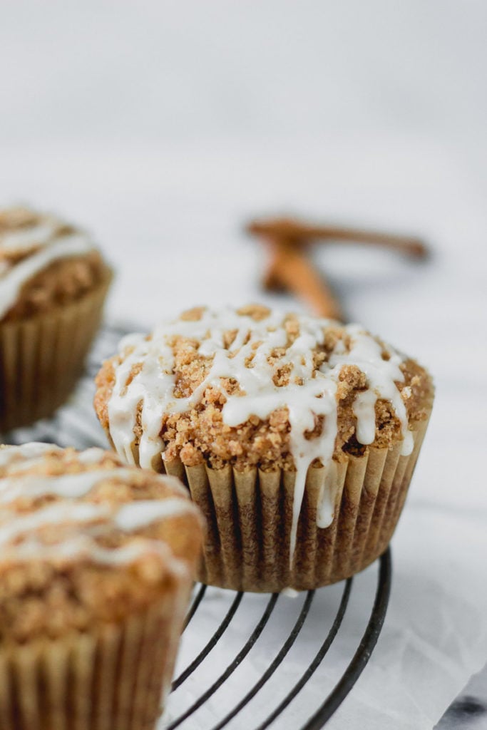 apple cider streusel muffins on cooling rack with drizzle by fork in the kitchen