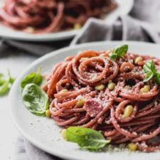 Red wine spaghetti with basil garnish on a plate.