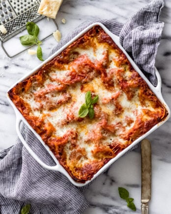 Vegetarian Spinach Ricotta Lasagna in white casserole dish with linen and knife by Fork in the Kitchen