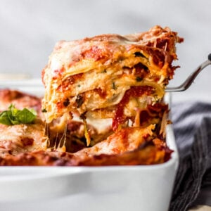 Scooping slice of spinach ricotta lasagna out of pan.