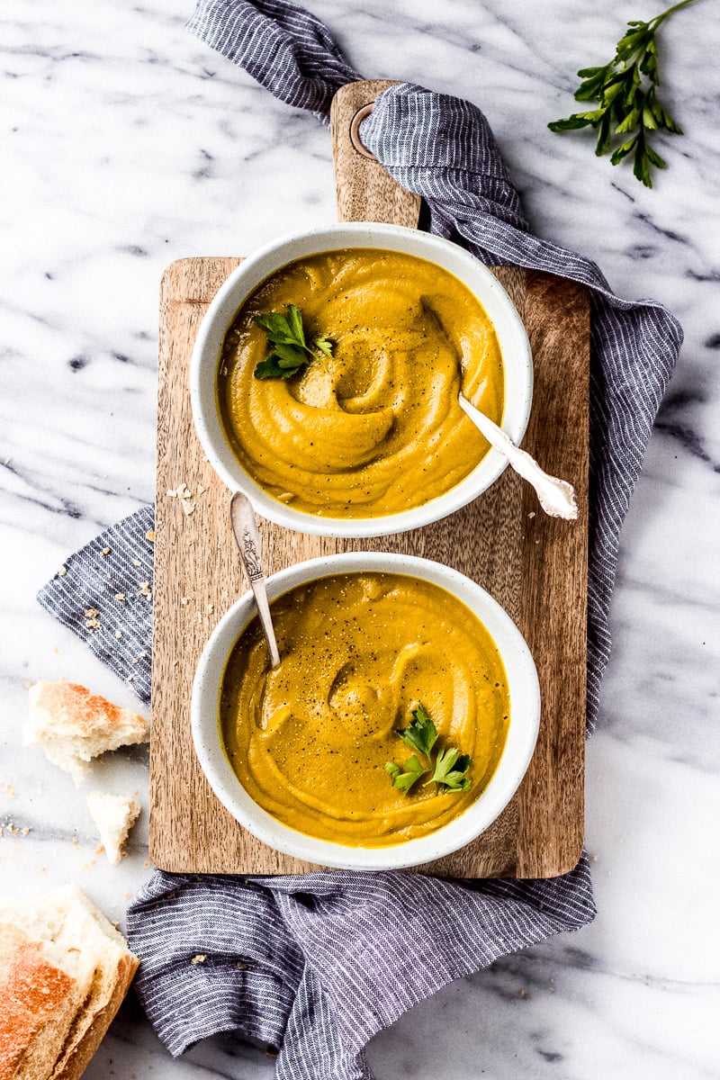 Curried Carrot Squash Soup in a white bowl with spoon by Fork in the Kitchen