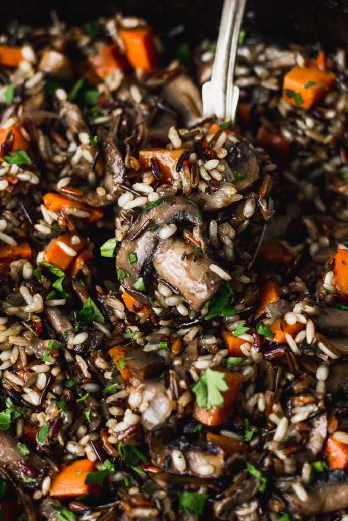 Herbed Wild Rice with Mushrooms on serving spoon by fork in the kitchen