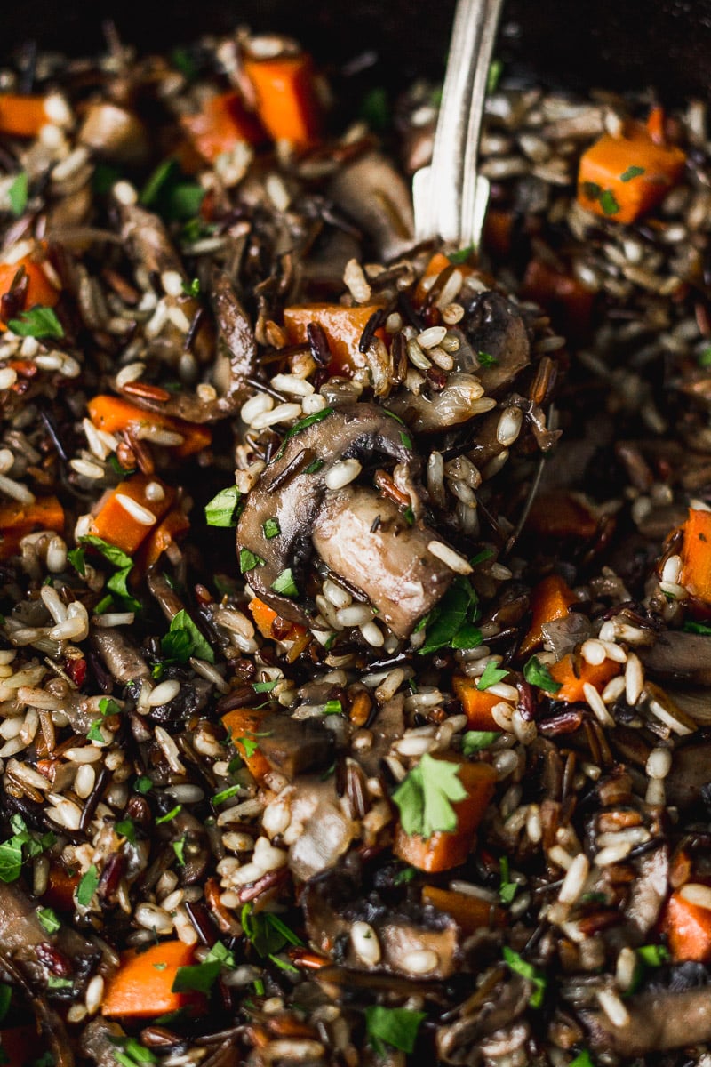 Wild rice with mushrooms in skillet with spoon.